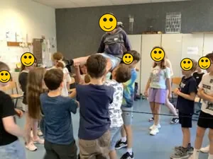 Anti-Mobbing-Training: Kinder tragen gemeinsam ein Kind — Teamübung, Gesichter zum Schutz der Kinder mit Smileys überdeckt