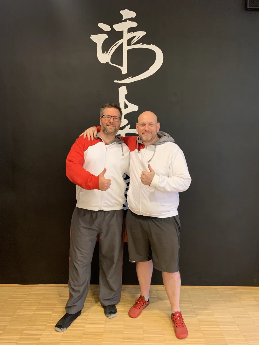 Daumen hoch vor der WingTsun-Kalligrafie nach der bestandenen Prüfung zum 2. Lehrergrad