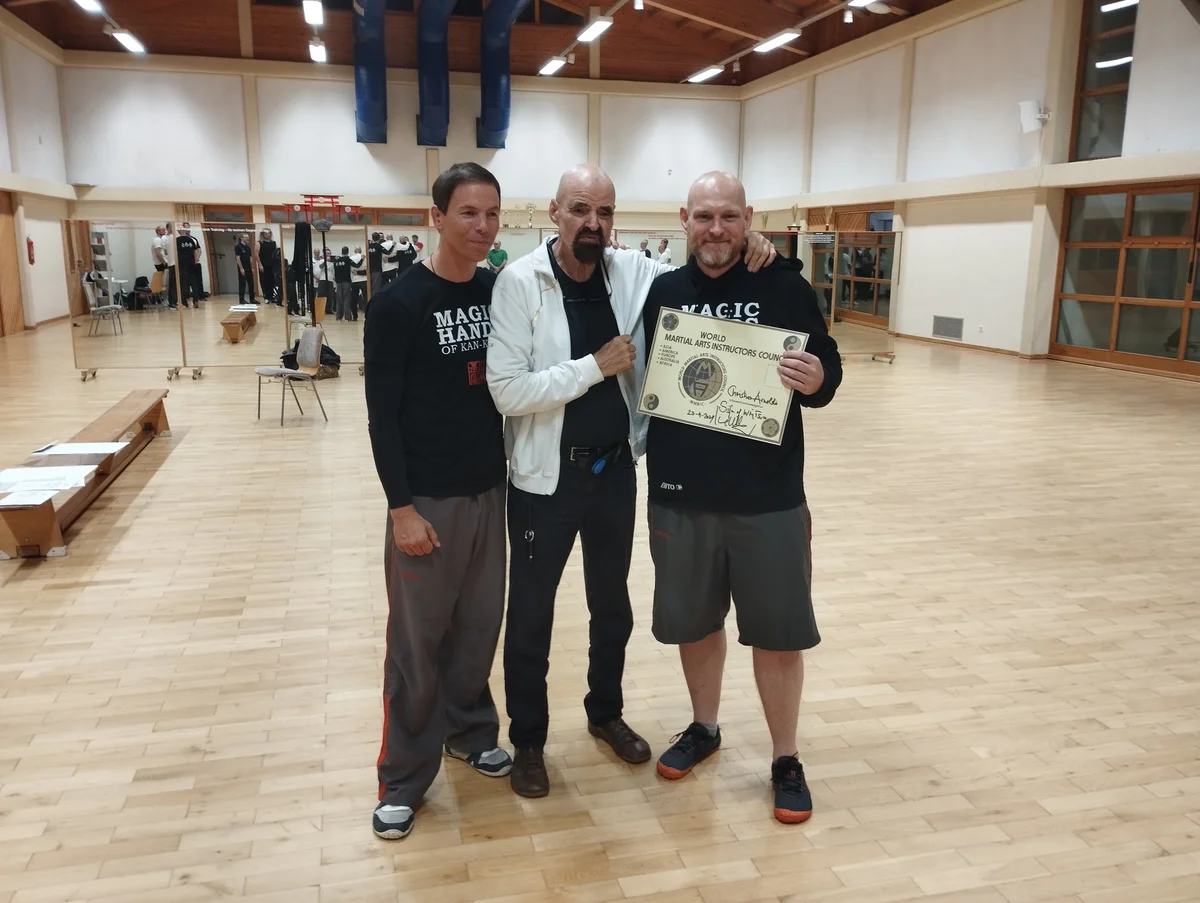 Christian Arnoldi mit der SiFu-Urkunde, daneben Großmeister Keith R. Kernspecht und SiFu Axel Lukas