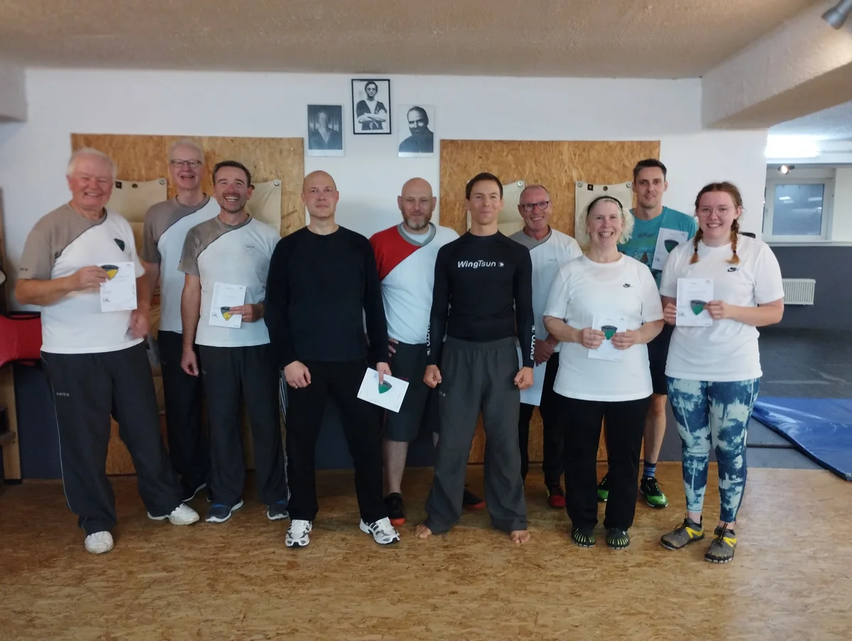 Gruppenfoto nach dem Prüfungslehrgang an der WingTsun Akademie — die Teilnehmer halten ihre EWTO-Urkunden