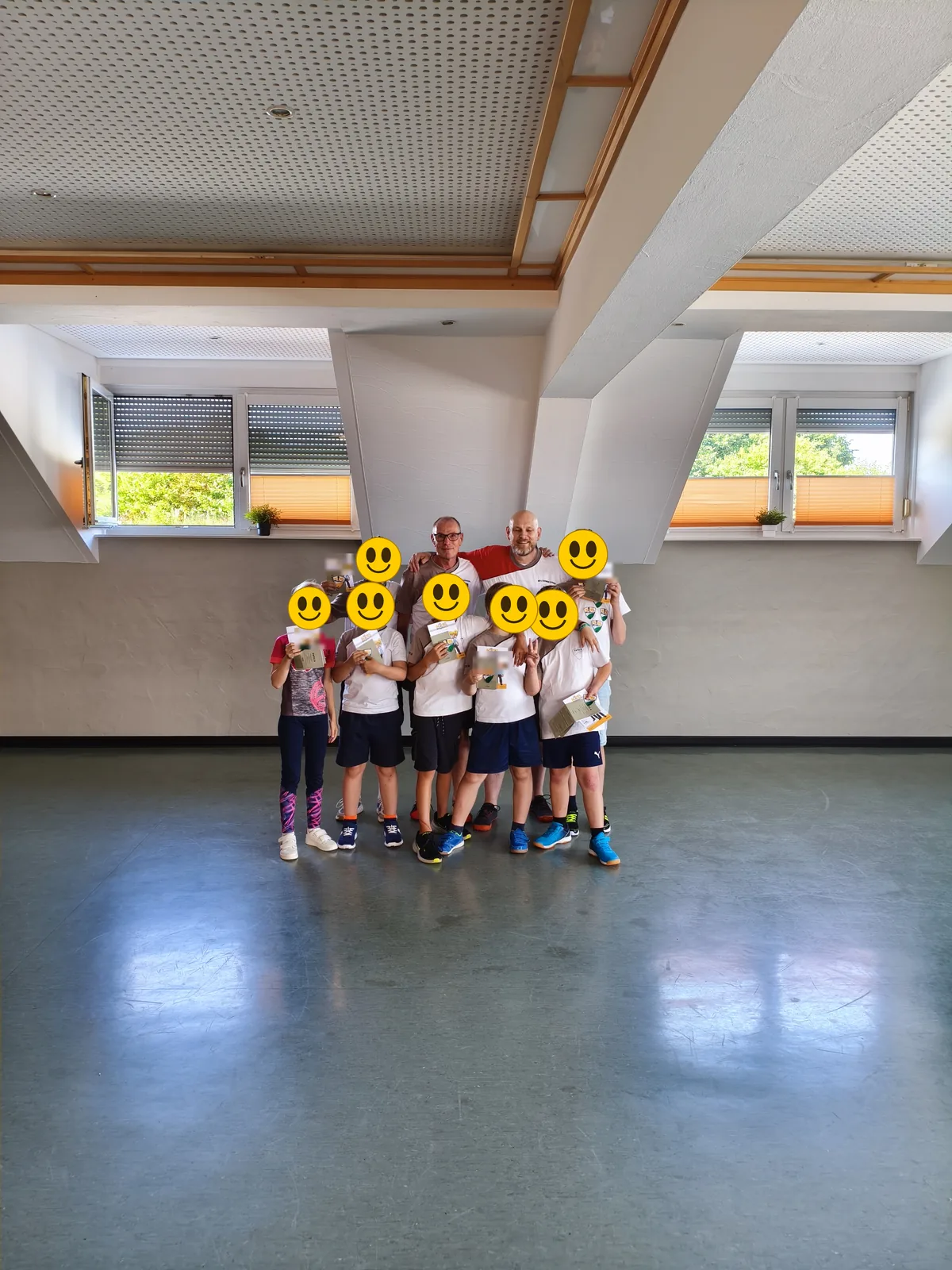 Zweite Prüfungsgruppe mit ihren Urkunden nach der bestandenen Schülergradprüfung — Gesichter zum Schutz mit Smileys überdeckt